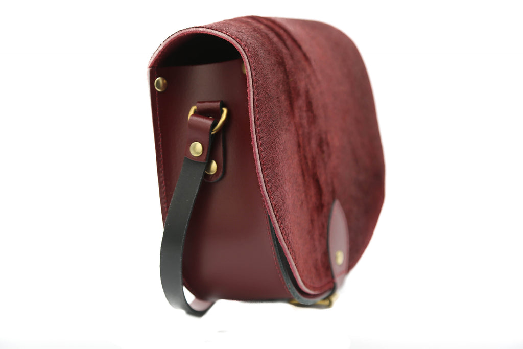 Burgundy cowhide hair Leather handmade saddle cross body handbag with adjustable belt buckle shoulder strap, made in London. Visit out customise section to choose your own colours and have a bespoke custom saddle bag made for you. A to Z Leather LTD